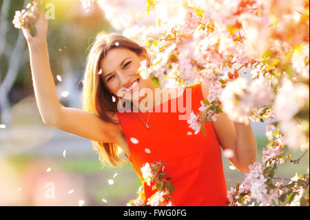 Belle femme avec des fleurs fleurs de printemps sur les arbres dans le jardin Banque D'Images