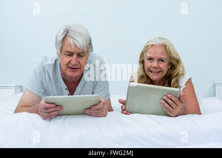 Couple using digital tablets tout en vous relaxant dans la chambre Banque D'Images