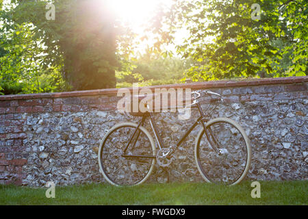 Un style vintage racer bike s'appuya contre un mur de briques et silex Banque D'Images