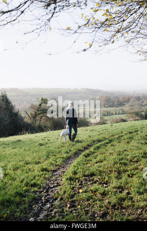 Une femme marche avec un chien sur un promontoire donnant sur la campagne. Banque D'Images