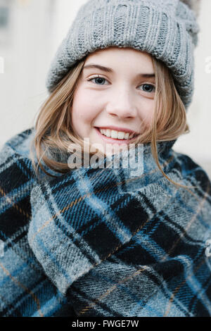 Une jeune fille dans un châle plaid tartan et woolly hat à l'extérieur l'hiver. Banque D'Images