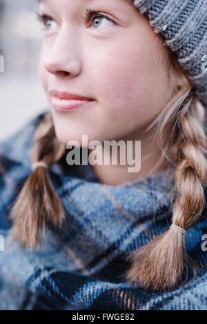 Une adolescente dans un châle plaid tartan et woolly hat à l'extérieur l'hiver. Banque D'Images