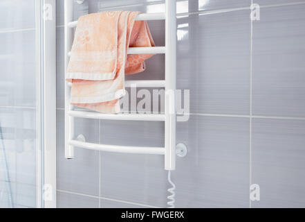 Vide salle de bains avec douche de couleur gris métal blanc derrière mur grille de réchauffage avec serviette rose pliée à haut Banque D'Images