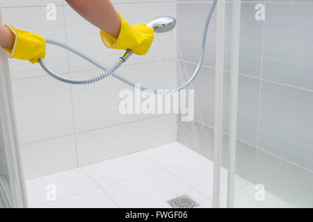 Personne non identifiable pulvériser de l'eau avec douche à main tête en bas en marbre de vidange avec porte coulissante Banque D'Images