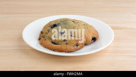 Un muffin aux bleuets fraîchement cuits sur une assiette blanche haut au-dessus d'une table en bois haut. Banque D'Images