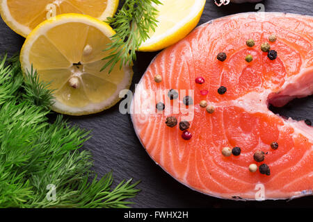 Poisson rouge steak de citrons sur un tableau d'ardoise. Banque D'Images