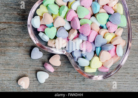 Comprimés vitamine colorés avec forme de coeur en plaque de verre sur fond de bois. Banque D'Images