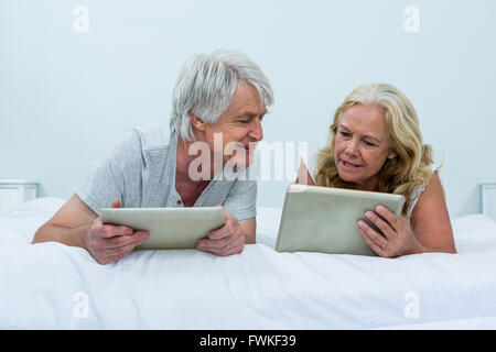 Senior couple talking lors de l'utilisation de tablettes numériques dans la chambre Banque D'Images