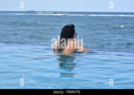 Une femme dans une piscine à débordement donnant sur l'océan à Porto Rico Banque D'Images