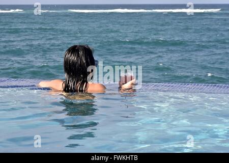 Une femme dans une piscine à débordement donnant sur l'océan à Porto Rico Banque D'Images
