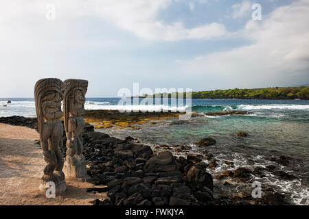Ki'féroce je statues montent la garde à la baie donnant sur Honaunau lieu de refuge sur la grande île d'Hawaï. Banque D'Images