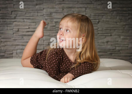 Petite fille sur le canapé Banque D'Images