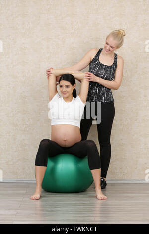 Femme enceinte faire l'exercice de remise en forme avec un entraîneur personnel Banque D'Images