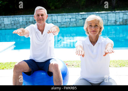 Portrait of senior couple doing aerobics at poolside Banque D'Images