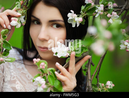 Attractive young woman posing with lilic fleurs dans Green Park à bright spring day pendant son temps libre. Grand portrait de belle fille aimer la nature. Banque D'Images