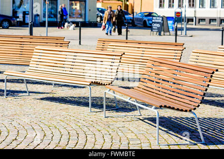 Simrishamn, Suède - 1 Avril 2016 : vide quelques bancs en bois sur la place de la ville avec les gens de se concentrer dans l'arrière-plan. Banque D'Images