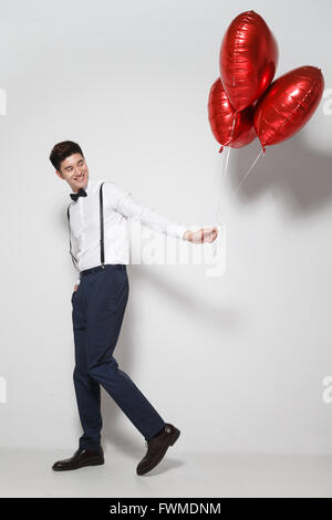 Jeune homme avec des ballons en forme de cœur Banque D'Images