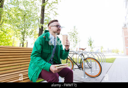 Heureux homme hipster eating sandwich avec du café Banque D'Images