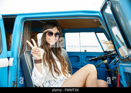 Femme hippie heureux montrant la paix en voiture fourgonnette Banque D'Images