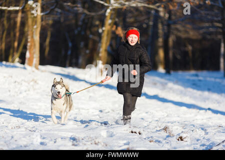 Adolescente avec un chien husky à l'heure d'hiver Banque D'Images