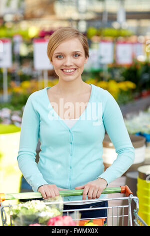 Femme heureuse avec panier et fleurs en boutique Banque D'Images