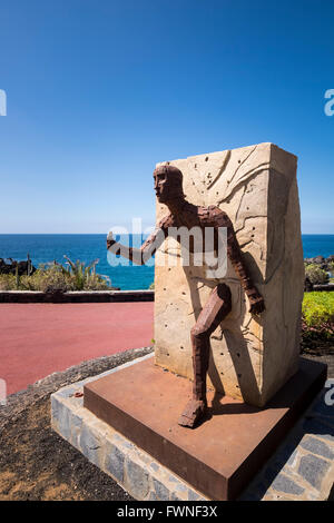 Homme qui court à travers la paroi en statue de pierre et de métal rouillé. Playa San Juan, Tenerife, Canaries, Espagne Banque D'Images