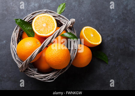 Oranges frais mûrs dans panier sur pierre sombre arrière-plan. Vue d'en haut Banque D'Images