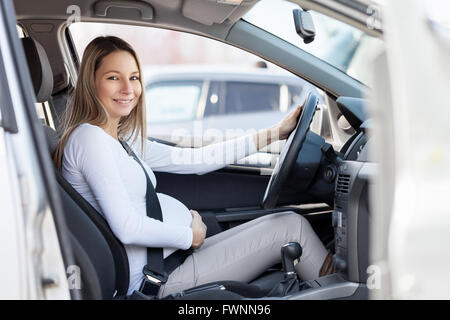 Femme enceinte conduisant sa voiture, le port de la ceinture de sécurité Banque D'Images