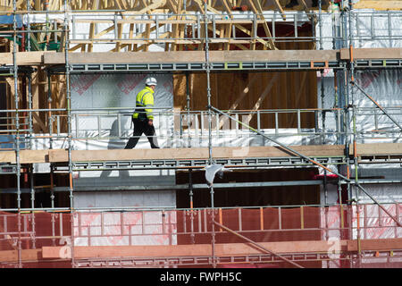 Une équipe de travailleurs à contrat construction bâtiment (charpentiers et menuisiers) travaillant sur la "première fix' travail structurel sur la coquille d'un cadre en bois nouveau bloc d'appartements Appartements Maisons, UK Banque D'Images