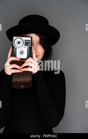 Hipster photographe : un jeune, femme fille, fin de l'adolescence au début de la vingtaine, mince, les cheveux bruns, tenant un vieux rétro appareil photo Kodak film analogique Banque D'Images