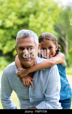 Grand-père souriant avec petite-fille at yard Banque D'Images