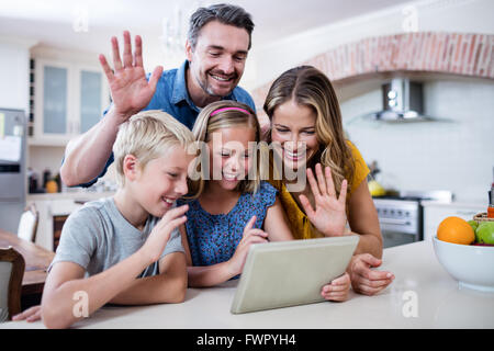 Les parents et enfants des signes avec la main pendant l'utilisation de tablette numérique pour le chat vidéo Banque D'Images