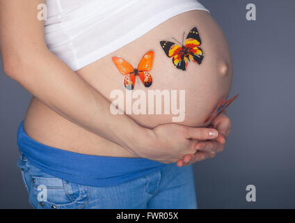 Portrait femme enceinte stress anxieux avec papillons dans l'estomac studio isolé sur fond gris Banque D'Images