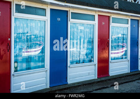 Chalets sur la plage de Cromer, Norfolk, avec le rouge et le bleu des portes et des réflexions dans les fenêtres Banque D'Images
