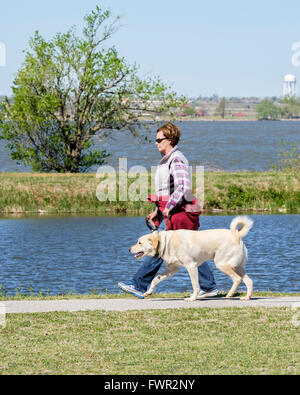 A middle-aged Woman femme entre son Labrador Retriever sur les sentiers du lac Overholser inh Oklahoma City, Oklahoma, USA. Banque D'Images