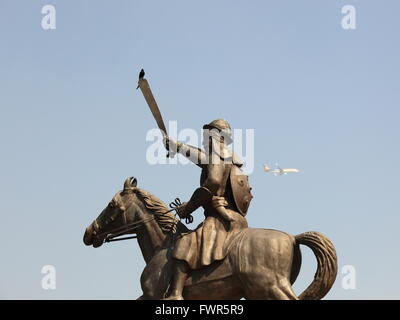 A Black Drongo, situé sur l'épée d'un guerrier statue au Baba Banda Singh Bahadur monument comme un avion de passagers par les mouches. Banque D'Images