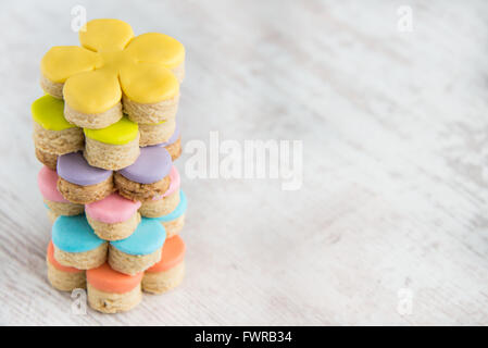 Libre de forme de fleurs colorées des fondants couverts des cookies sur un fond de bois blanc Banque D'Images