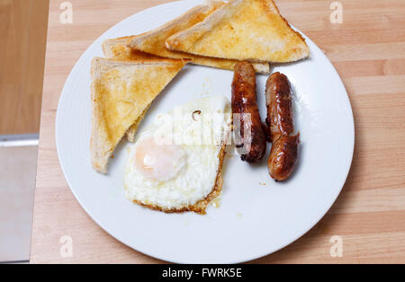 Œuf frit, et des saucisses avec du pain grillé sur une plaque blanche Banque D'Images