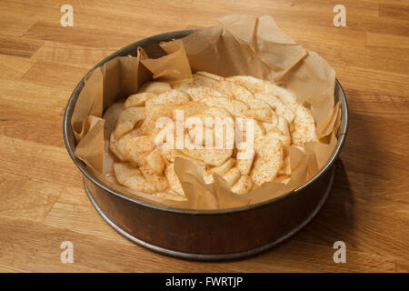 Apple pie tarte dans un moule à charnière de métal debout sur une table en bois, avec des tranches de pomme et de cannelle sur le dessus Banque D'Images