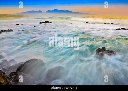 Sur les ondes de Hookipa beach Maui avec vue éloignée sur les montagnes de West Maui avec une couche de brouillard Banque D'Images