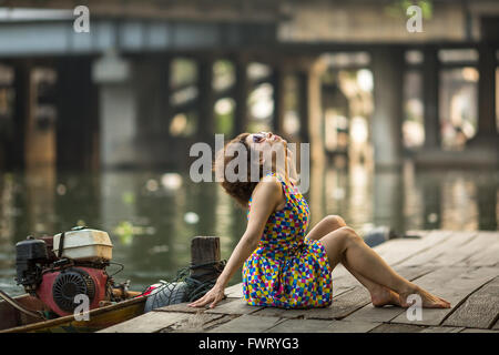 Belle asiatique femme assise sur une rivière en bois jetée. Banque D'Images