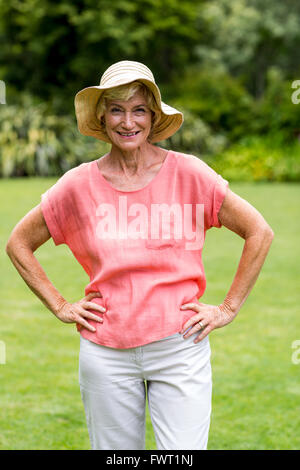 Happy senior femme avec ahnd sur la hanche at yard Banque D'Images