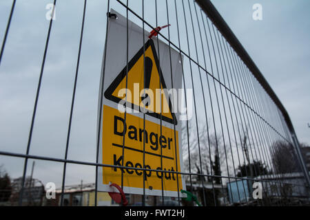 Un "danger Garder hors' signer devant beaucoup de ferraille et des bâtiments abandonnés. Banque D'Images