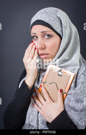 Femme musulmane gémissant sur une vieille photographie dans un cadre Banque D'Images