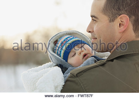 Man carrying baby boy outdoors in winter