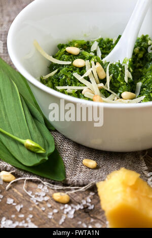 Le pesto ramson dans un bol blanc, de l'ail sauvage, noix de pin, le parmesan et l'huile d'olive sur un fond de bois Banque D'Images