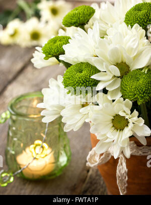 Bouquet de chrysanthèmes blancs et verts dans un vase en céramique sur un fond de bois Banque D'Images