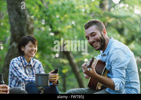 Les amis à jouer de la guitare à un camp site Banque D'Images