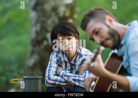 Les amis à jouer de la guitare à un camp site Banque D'Images