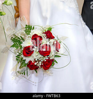 Bouquet de roses rouges dans sa main jusqu'à la mariée Banque D'Images